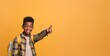© P - Smiling African American boy with high top haircut, pointing to the side, wearing a yellow plaid shirt and backpack against an orange background.