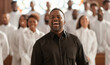 © Soloviova Liudmyla - African american man choir leader in black shirt signing with church choir wearing all white , people singing emotionally unfocused in background. Power of music and feith concept..