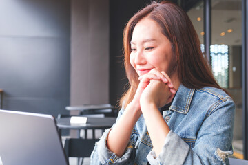 Wall Mural - Portrait image of a young woman working on laptop computer in cafe