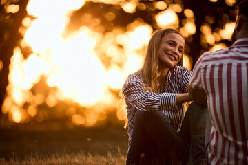 A lovely couple sitting at the park during the sunset.