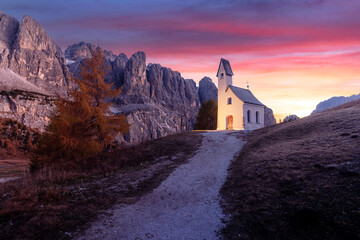 Wall Mural - cozy iiluminated chapel - kapelle ciapela on gardena pass, italian dolomites mountains. purple sunse