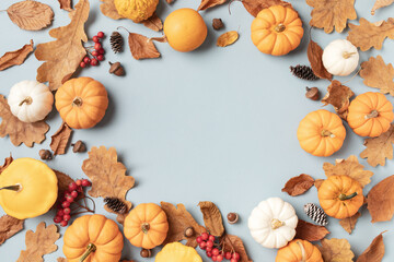 Wall Mural - Autumn frame from fall leaves, pumpkins and seasonal decorations on turquoise background top view.