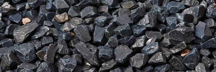 Poster - Various sizes of black crushed stone aggregate form a textured surface, commonly used in construction and landscaping projects under bright sunlight