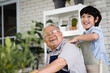 © ronnachaipark - A man and a boy are smiling and hugging each other.A boy massages his grandfather's back for comfort.