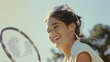 © VK Studio - A cheerful young girl with hair blowing in the wind enjoys playing tennis on a sunny day, her radiant smile framed by the tennis racket and the bright blue sky.