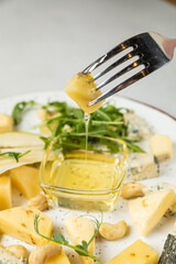 Cheese plate with crackers, nuts and herbs on white background