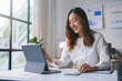 © amnaj - Smiling asian businesswoman working on digital tablet, analyzing financial data with graphs and charts