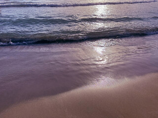 Ocean waves on sand beach at summer evening 