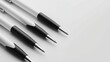 © Lull - White and black pens on a table. Four pens, with white barrels and black caps, are laid out in a row on a white surface.