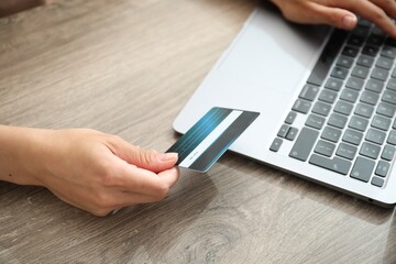 Canvas Print - Woman with credit card using laptop at wooden table indoors, closeup