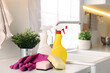 © New Africa - Cleaning service. Detergents, sponges and gloves on table in kitchen