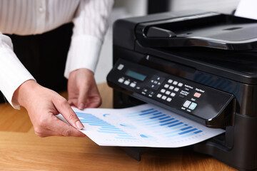 Woman using modern printer at workplace indoors, closeup