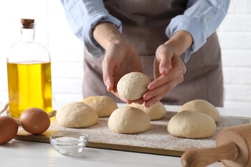 Wall Mural - Woman making dough ball at white wooden table, closeup