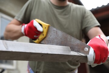 Wall Mural - Man sawing wooden plank in backyard, closeup