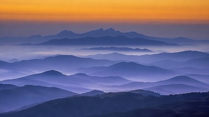 Wall Mural -   A stunning mountain range viewed at sunset from a mountaintop's peak in the foreground, with the sun setting beyond the horizon