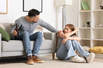 Wall Mural - Bruised young woman and her drunk husband at home. Domestic violence concept