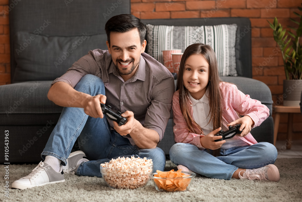 Father with his little daughter playing video game at home
