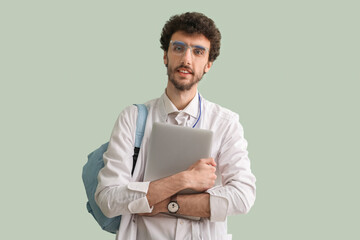 Canvas Print - Male student with laptop on green background