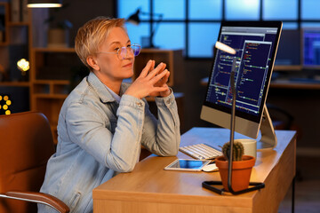 Wall Mural - Mature female programmer working in office at night