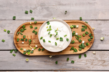 Sticker - Bowl of tasty sour cream with green onion on light wooden background