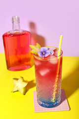 Wall Mural - Fresh summer cocktail with carambola and flower on yellow table near lilac wall