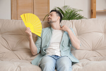 Sticker - Young man with fan on sofa at home