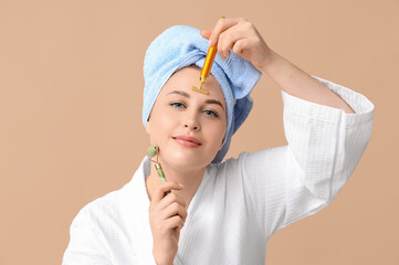 Sticker - Beautiful young woman using facial massage tools on beige background