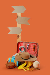 Wall Mural - Open suitcase, accessories and cardboard sign on orange background. Travel concept