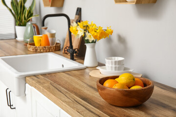 Wall Mural - Citrus fruits and daffodil flowers on kitchen counter. Closeup