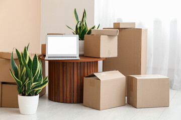 Poster - Blank laptop on table with moving boxes and plants in room