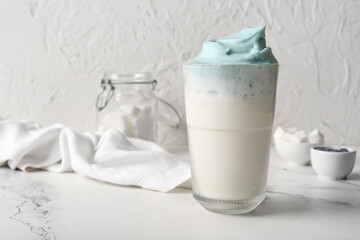 Sticker - Glass of blue dalgona matcha latte and napkin on marble table, closeup