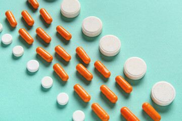 Wall Mural - Many different pills on turquoise background, closeup