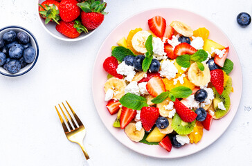 Wall Mural - Fruity summer salad with fresh berries, ricotta cheese, banana, kiwi and mint, white background, top view