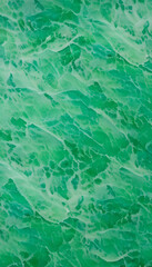 An abstract pattern of green waves resembling water surface, with a textured appearance a vibrant green color with a marbled effect, resembling jade. The light creates movement in the design.