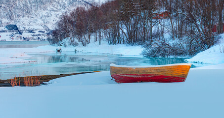 Wall Mural - red wooden boat covered with layers of snow - beautiful winter landscape with snow covered red house