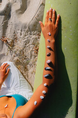 Wall Mural - Young woman sitting on beach with sea shells laid her arm