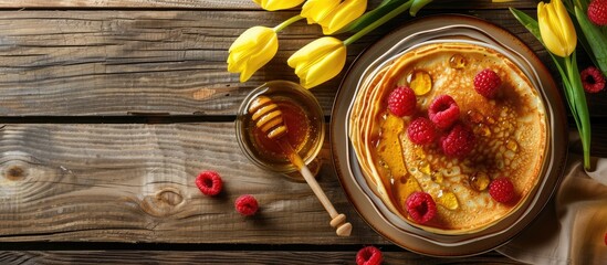 Poster - Traditional Russian pancakes with berries and honey on a wooden table for the spring holiday Shrovetide accompanied by yellow tulips with copy space image