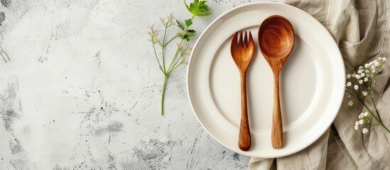 Poster - Rustic vintage dining set with a wooden spoon fork and white plate on a napkin made from water hyacinth against a light gray concrete background with an empty plate perfect for a copy space image in