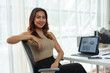 © crizzystudio - Confident Asian businesswoman, independent business owner sitting in a chair at a desk A smiling face uses a laptop to work and analyze financial report documents. office investment.