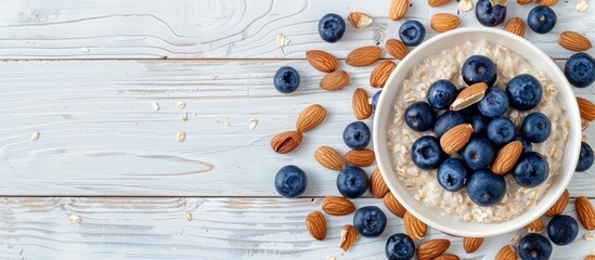 Aufkleber - Top view of a white wooden background with a breakfast oatmeal featuring blueberries and almonds providing copy space image