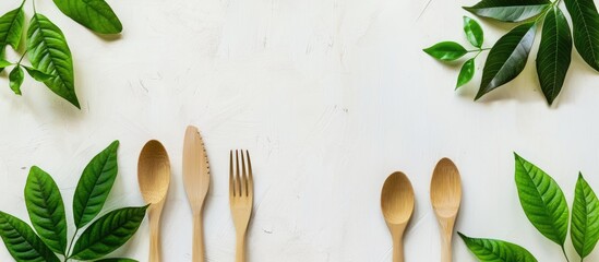 Poster - Eco friendly cutlery on a light background for food delivery with a green leaf frame on a white background emphasizing an eco conscious concept Copy space image included