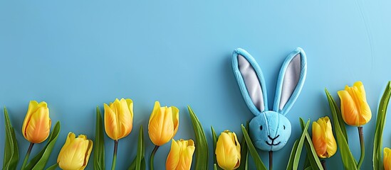 Canvas Print - A festive Easter themed picture featuring cute blue bunny ears vibrant yellow tulips on a blue backdrop creating a charming copy space image from above