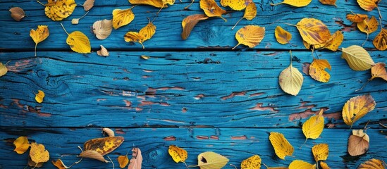 Fototapete - Season wallpaper featuring bright yellow autumn leaves against a rustic blue backdrop with copy space image