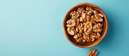Aufkleber - Walnut kernel halves arranged attractively in a wooden bowl captured from above on a colored background focusing on healthy eating and super foods with copy space image