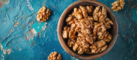 Canvas Print - Walnut kernel halves arranged attractively in a wooden bowl captured from above on a colored background focusing on healthy eating and super foods with copy space image