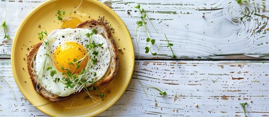 Aufkleber - Top view of a healthy breakfast scene a yellow plate holds toast topped with an egg and micro greenery on a white wooden surface offering copy space image