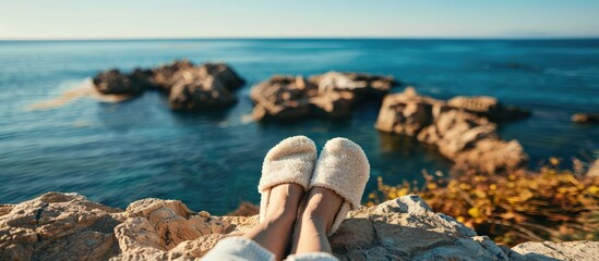 Poster - Legs wearing slippers by the seaside with a scenic background perfect for copy space image