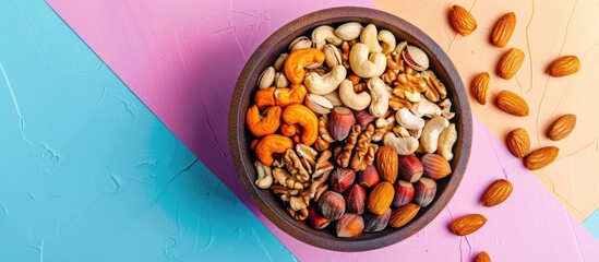 Aufkleber - Top view showing a variety of nuts like cashews hazelnuts walnuts and almonds in a wooden bowl on a colorful table with room for text or graphics in the image. Creative banner. Copyspace image