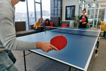 Wall Mural -  Business colleagues take a break from work to enjoy a game of table tennis, fostering teamwork and camaraderie in the workplace