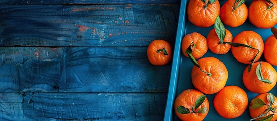 Poster - Top down view of a tray full of ripe tangerines positioned on a blue wooden surface allowing for the inclusion of text in the copy space image